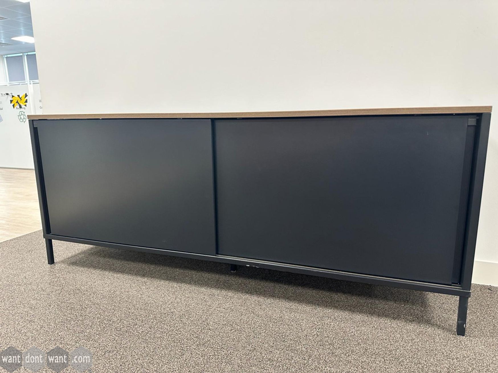 Used Knoll black credenzas with walnut tops, sliding doors and 2 shelf levels.