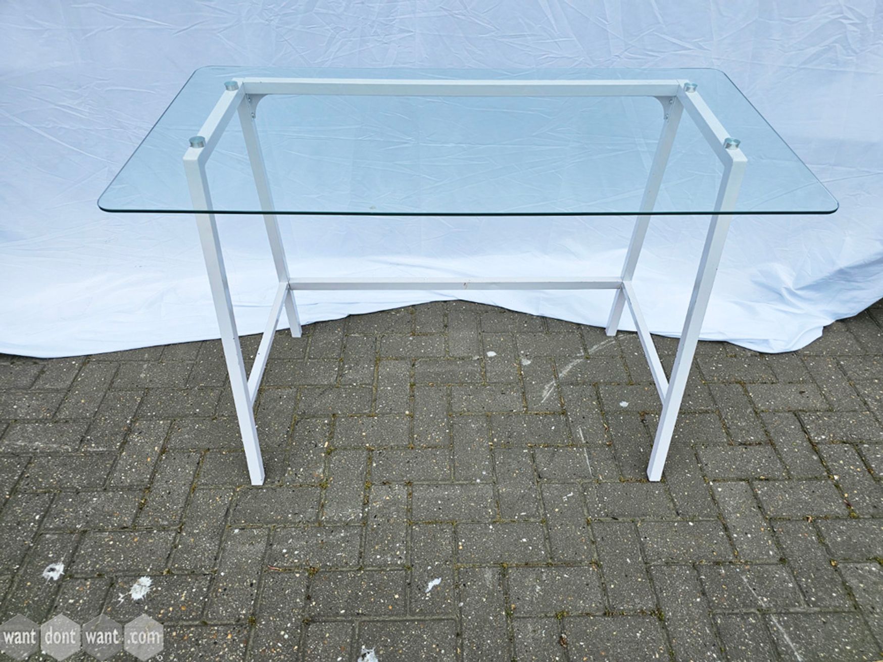 Used glass top table on white metal frame.