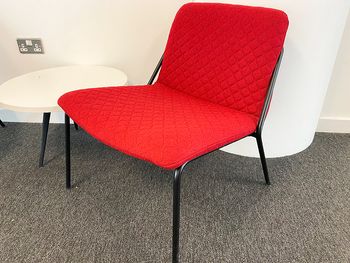 Used 'Sling' lounge chairs in red coloured quilted fabric with black metal legs.